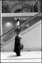 Hunched woman with man apparently standing on her